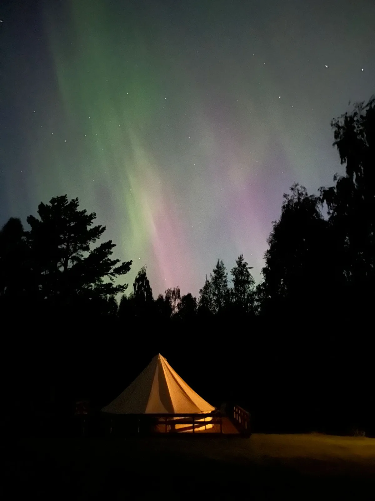 Noorderlicht boven een verlichte glampingtent